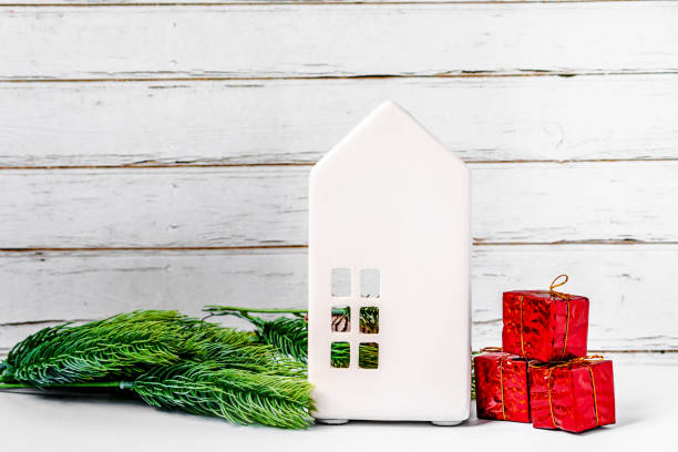 istock Christmas interior decoration with white ceramic house and Christmas tree toys on white rustic background with copy space 1287577659