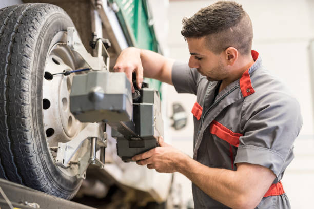 istock Mechanic calibrating wheels with computer and technology equipment 1287582511