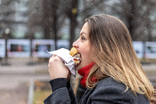 Young hungry woman eats Burger and takes lunch break outdoors in Park.Fast food. Takeaway food concept Young hungry woman eats Burger and takes lunch break outdoors in Park.Fast food. Takeaway food concept. perpetual motion machine stock pictures, royalty-free photos & images