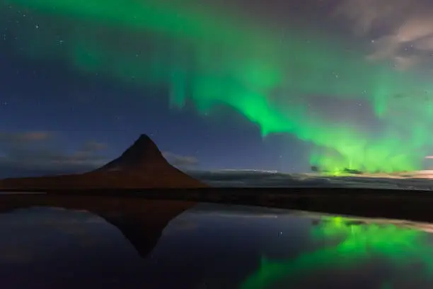 Photo of Northern lights in Iceland. Landscape full of kp5 Aurora Borealis. Amazing nightscape at Kirkjufell, scenic travel destination. Green sky full of stars.