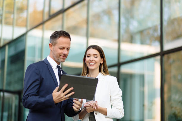 istock Two business people discussing work on tablet computer outdoors 1287588538