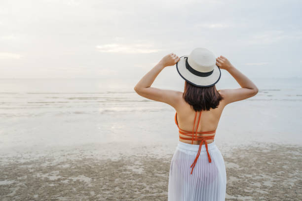 istock cheerful woman in bikini standing at sea beach 1287588608