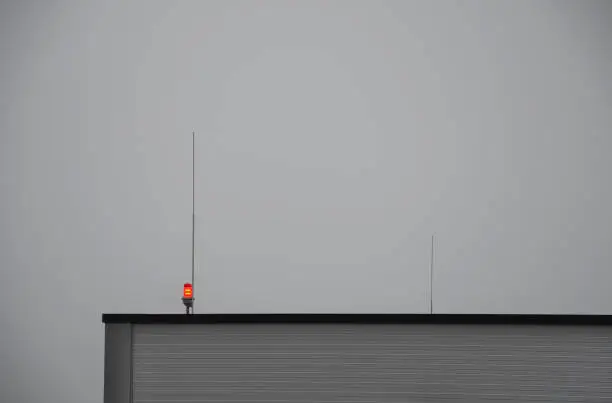 Photo of lightning conductors and red parking lights need to be installed on the roofs of tall buildings and industrial halls due to collisions with airplanes and helicopters in fog and at night. near airport