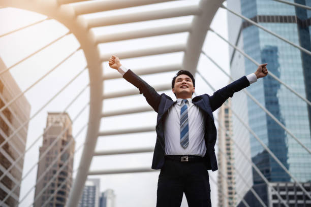 istock successful business man with arms raised in city 1287589551