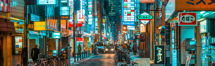 Commuters and traffic in the neon lit streets of the Umeda district beside the restaurants and bars of downtown Osaka, Japan’s vibrant second city.