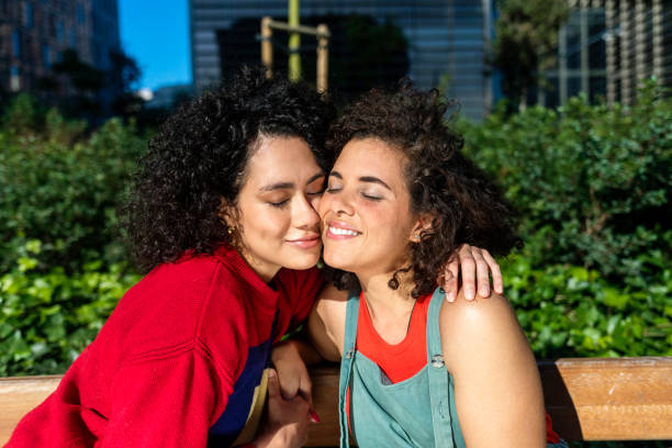 istock Smiling lesbian couple embracing and relaxing on a park bench 1287590619