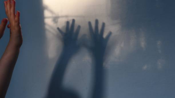 istock Defocus shadows of kid hands on stucco wall surface with copy space. Halloween concept 1287592523
