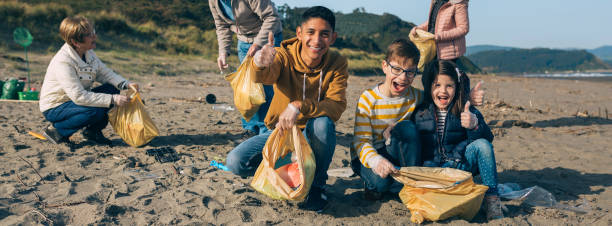 istock Young man and children cleaning the beach 1287593499
