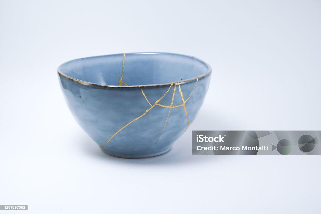 Kintsugi blue bowl repaired with gold. Kintsugi blue bowl. Gold cracks restoration on old Japanese pottery restored with the antique Kintsugi restoration technique. The beauty of imperfections. japanese pottery repair gold. japanese art of repairing cracks with gold. japanese art of fixing broken pottery Kintsugi Stock Photo