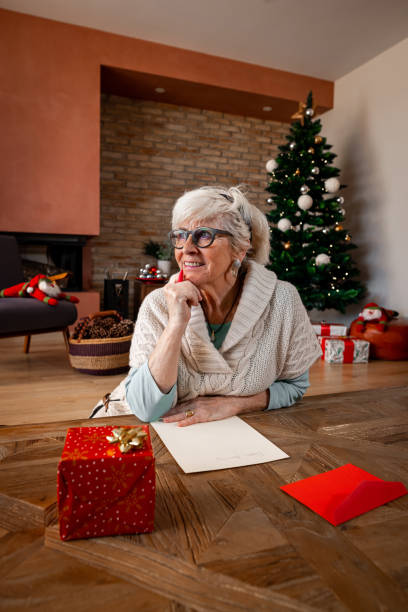 istock Smiling lady thinking and writing a letter for Christmas. 1287597116