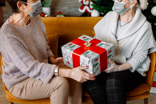 istock Christmas wrapped gift with two Elderly female friends. 1287599228