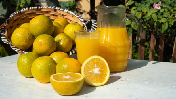 istock Oranges and orange juice on an old white table with blurred nature in the background, natural light, selective focus. 1287601603