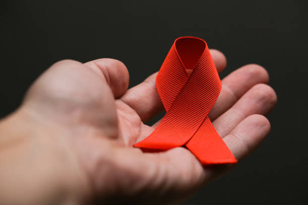 istock AID red ribbon in hand on gray dot 1287602828