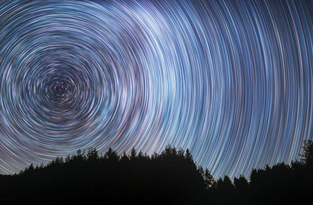 hermoso cielo estrellado con senderos estelares detrás de la silueta de los árboles.  fondo espacial. fondo abstracto de exposición larga. - star trail galaxy pattern star fotografías e imágenes de stock