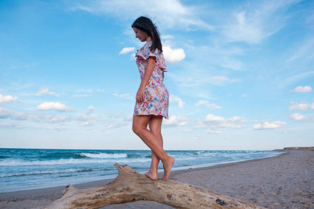 istock Woman walking on trunk on the beach 1287608621