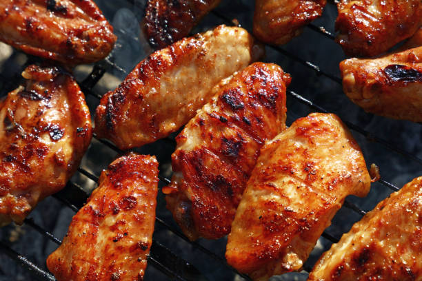 Chicken buffalo wings cooked on BBQ grill Close up chicken buffalo wings cooked on bbq smoke grill, high angle view metal grate photos stock pictures, royalty-free photos & images