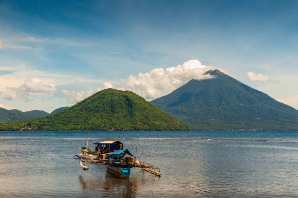 Scenic view of a boat on tropical ocean with vulcano in background, Ternate, Maluku, Indonesia Scenic view of a boat on tropical ocean with vulcano in background, Ternate, Maluku, Indonesia ternate stock pictures, royalty-free photos & images