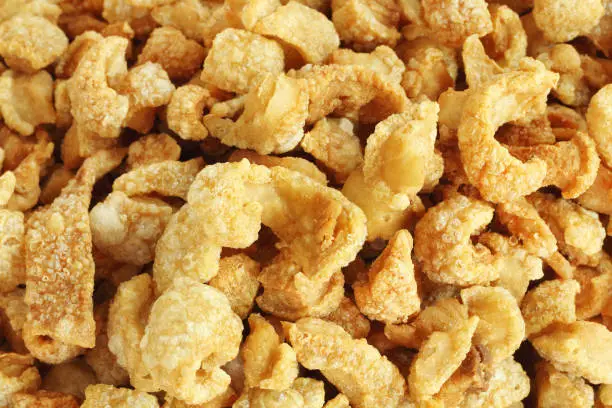 Photo of Close up of pork snack or pork scratching at market, crispy fried pork skin and blistered is traditional food in the north of Thailand.