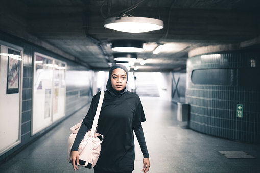 young muslim sports woman with hijab standing in subway station in Berlin and looking to camera