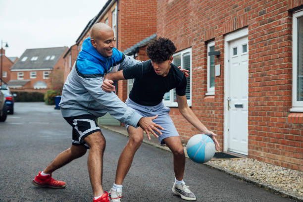 Father Son Bonding A father and his teenage son playing basketball outside the front of their house in the North East of England. bouncing photos stock pictures, royalty-free photos & images