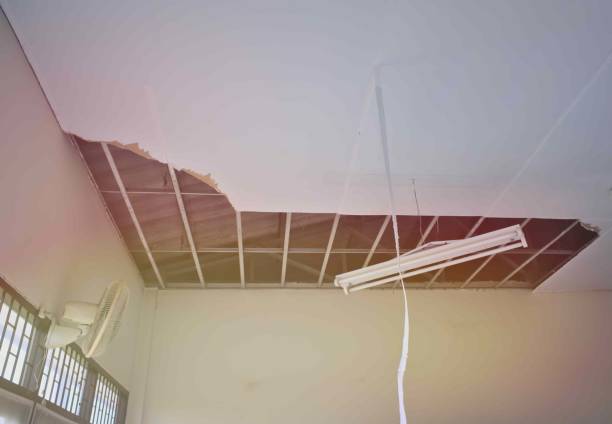 istock White broken ceiling,iron frame, hanging lamps is damaged. Ceiling fan. Damaged interior hall. 1287616590