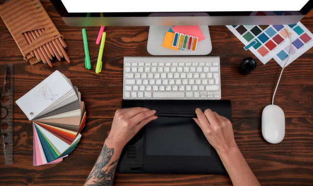 istock Professional web designer. Top view of male hands using digital graphics tablet and desktop in the office or studio. Workplace with graphic tablet, keyboard, computer and color swatches 1287616626