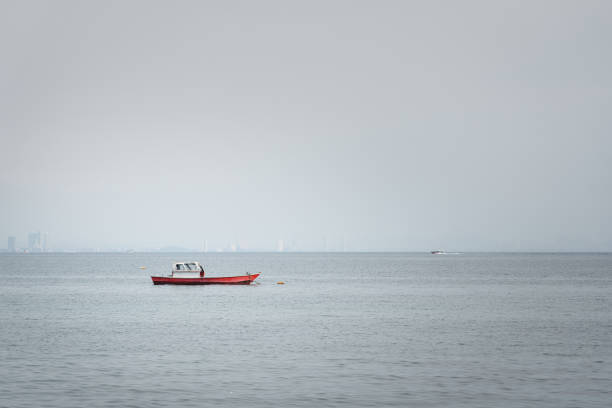 A local wooden fishing boat is floating on the ocean with misty  environment in the morning.