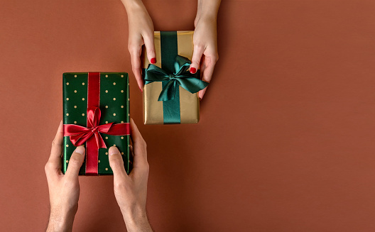 Woman giving her boyfriend a wrapped Christmas gift.Christmas giftboxes with tidewater green ribbon. Hands Giving Gifts Close-up.