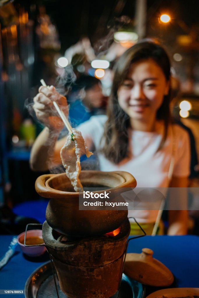An asian chinese woman eating Thai style Jim Jum hotpot Young asian woman tourist eating Thai style Jim Jum hotpot at Bangkok street during night time Market Stall Stock Photo