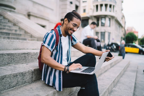 istock Smiling african american hipster guy in eyewear for vision correction typing on laptop computer share content in blog on freelance job,cheerful dark skinned male student browse online course on laptop 1287619623