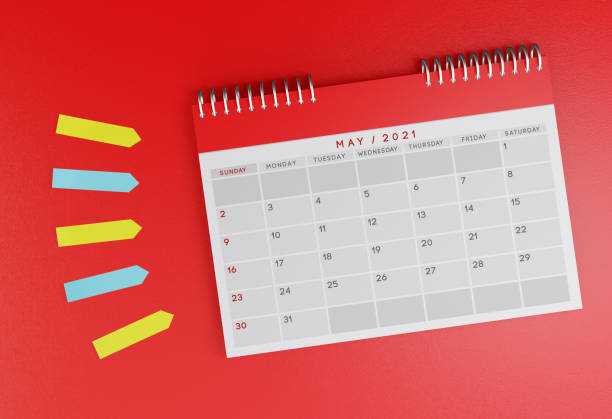 istock May 2021 desk calendar on a red background. With colorful sticky note papers next to it. 1287619811