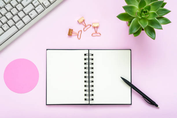 istock Flat lay of a pink desk with a keyboard, blank notebook, and a ballpoint pen 1287620964