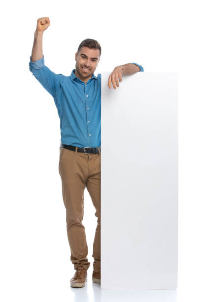 istock casual man leaning on a long billboard and celebrating succes 1287624166