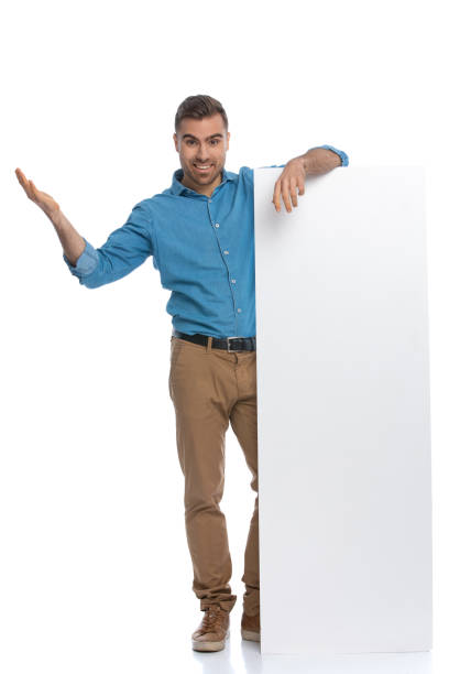 istock handsome casual man leaning on a long billboard and smiling 1287624190