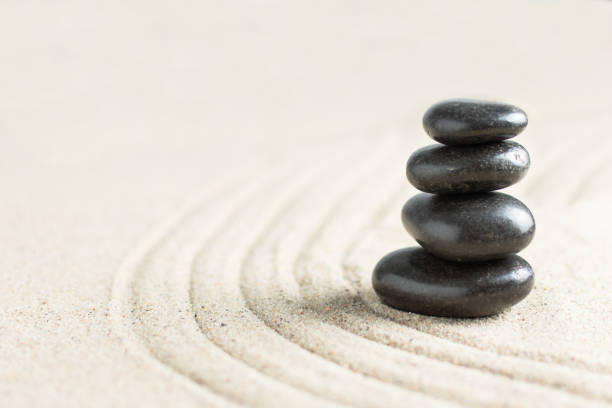 istock Black zen stones in a stack on beach sand. Meditation stone background. 1287626532
