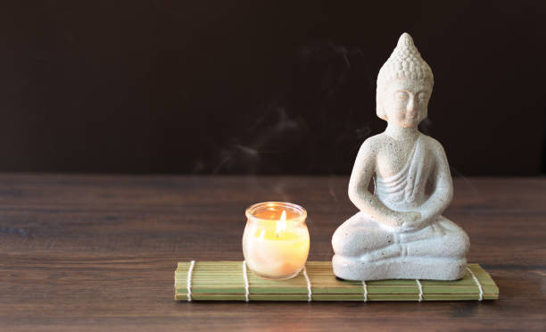 istock Buddha figure in meditation with burning candle on brown  background. 1287626556
