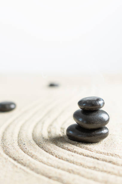 istock Black zen stones in a stack on beach sand. Meditation stone background. 1287626579