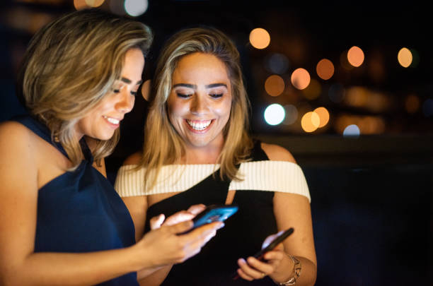 istock Stylish women smiling at a text while standing on a balcony at night 1287627150