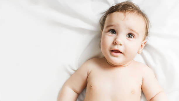 un niño gracioso. retrato de un bebé lindo de 6 meses de edad acostado en una manta blanca. concepto de infancia - 6 11 meses fotografías e imágenes de stock