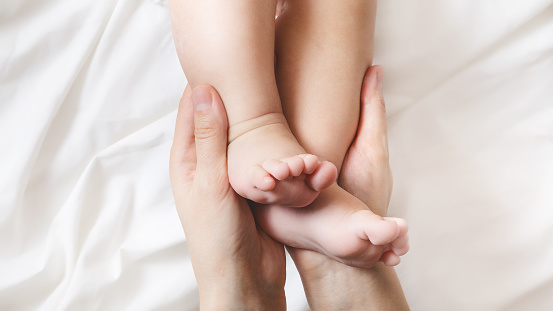 mom is holding the baby's tiny feet. Small baby feet on female hands close up. Happy family concept. Beautiful conceptual image of fatherhood. top view. copy space