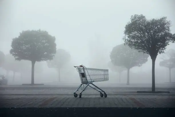 Photo of Abandoned shopping cart on parking lot in thick fog