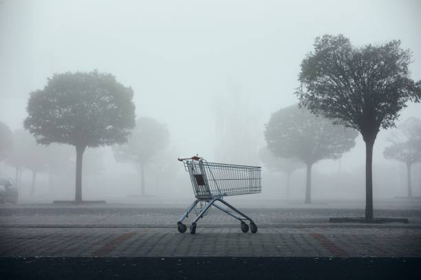 abandoned shopping cart on parking lot in thick fog - abandonado imagens e fotografias de stock
