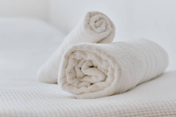 istock Folded white towels on bed, close up view 1287633398