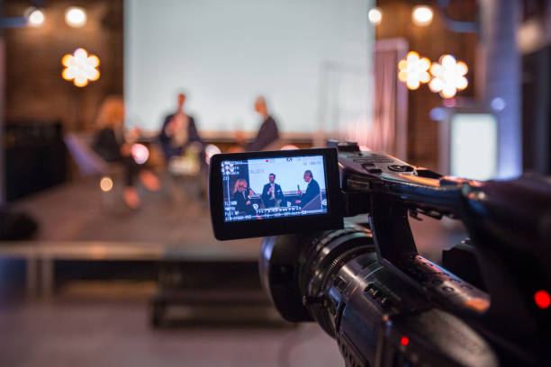 Businesswoman and businessmen during online seminar Businesswoman and businessmen discussing during online seminar, sitting on armchairs on the stage. Focus on video camera. conference event stock pictures, royalty-free photos & images