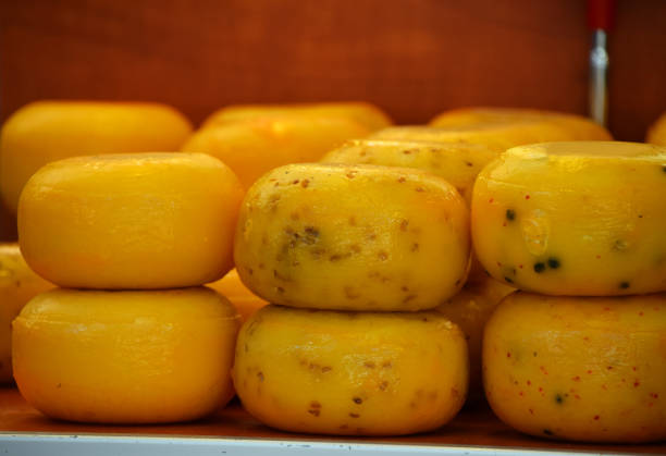 Close up selection of whole small heads of hard cheese on retail display, low angle view