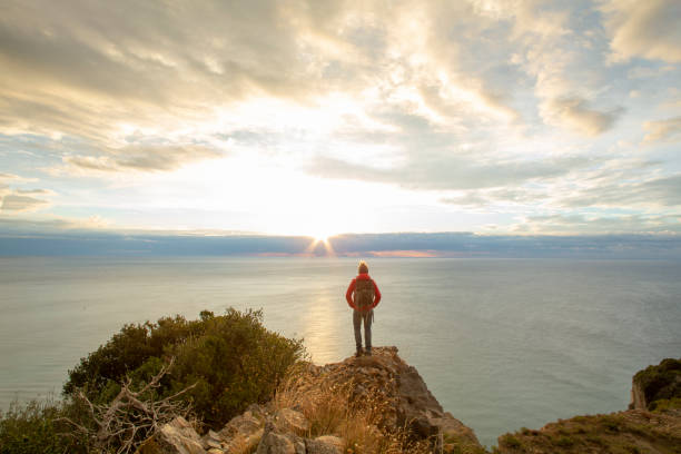 istock Hiker relaxes coastal cliff at sunrise 1287636729