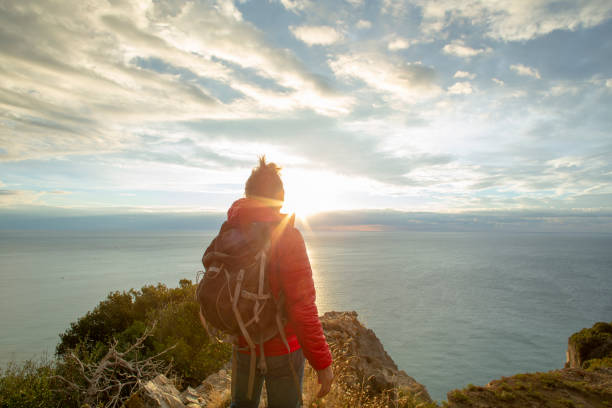 istock Hiker relaxes coastal cliff at sunrise 1287636755