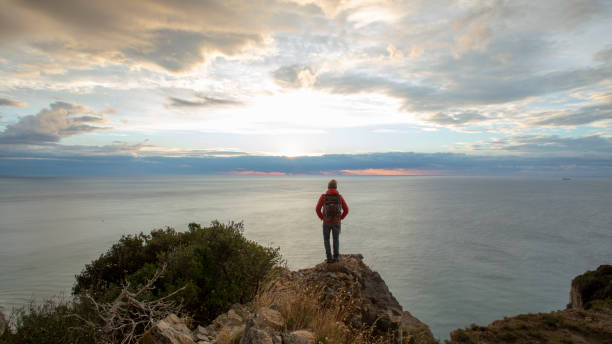 istock Hiker relaxes coastal cliff at sunrise 1287636756