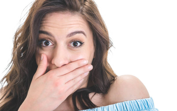 istock Surprised young woman covers her mouth keeps puppet eyes, isolated on white background. Astonished girl. Amazement concept 1287636787