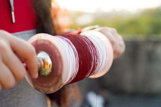 Man holding a charki phirki thread spool in the crook of his elbow and winding it with the other hand to ensure taughtness for the famed kite fighting festival of makar sankranti uttarayana stock photo